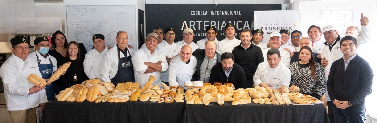 Josep Pascual junto a los maestros panaderos de Prosepan, frente a una mesa con los panes elaborados en la capacitación