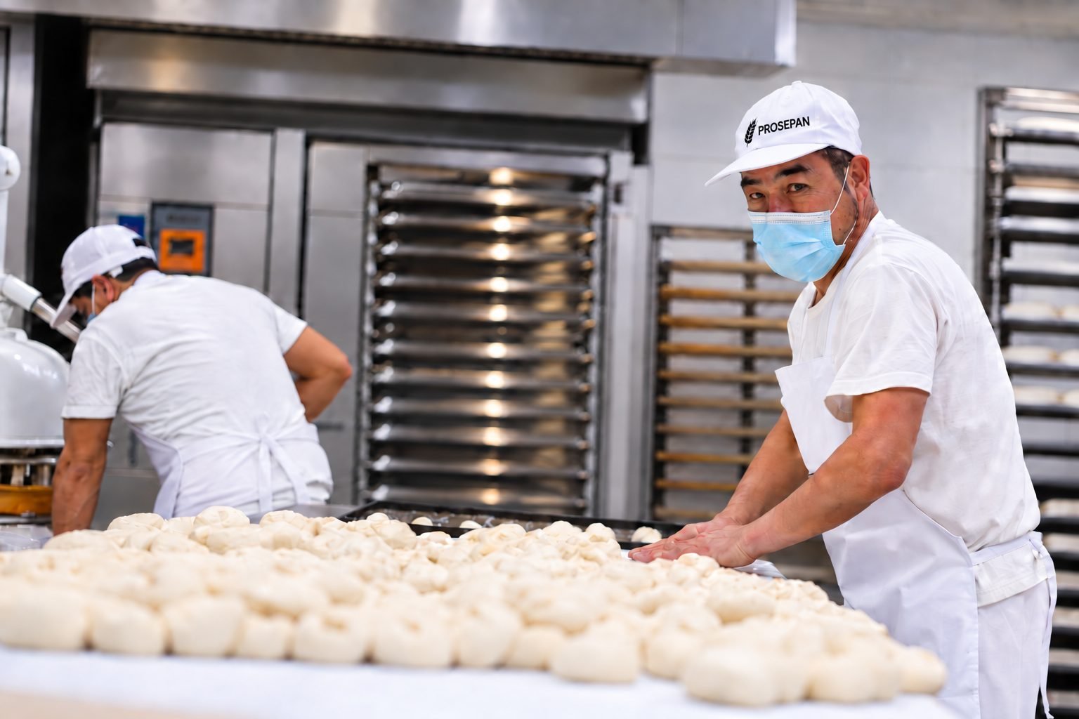 Maestros panaderos Prosepan formando piezas de masa frente al horno